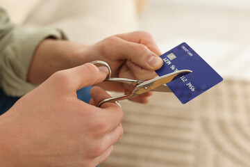 Man cutting his credit card indoors, closeup