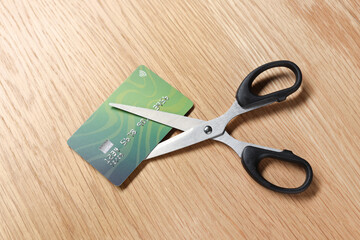 Credit card and scissors on wooden table, top view