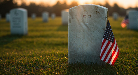 Gravestone with American flag in cemetery at sunset