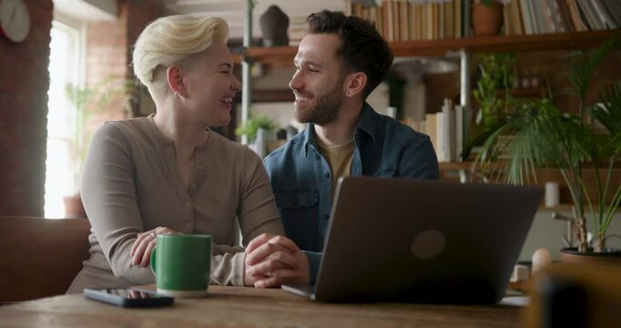 Couple at home Kissing as they apply for a home loan on a laptop