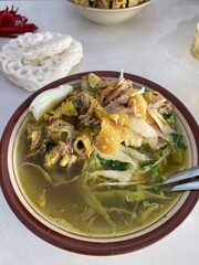 A bowl of chicken soup with various savory ingredients is presented