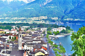 Aerial view of Ascona with surrounding mountains, forest, lake, and shoreline
