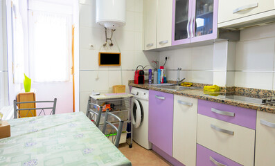 A kitchen with a white and purple color theme