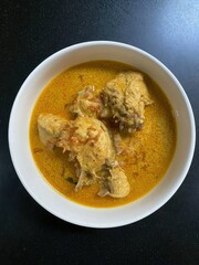 A white bowl of creamy yellow chicken curry sits perfectly