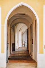 Explore the hidden charm of Ciutadella with this image of an arched passage, featuring architectural arches, a tiled floor, and a distant bicycle. Ideal for travel, culture, and architectural themes