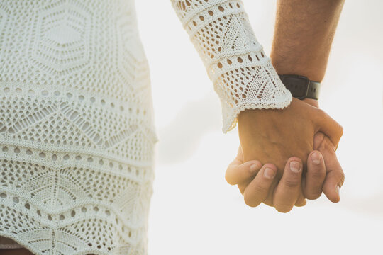 Casal de m&atilde;os dadas no por do sol.