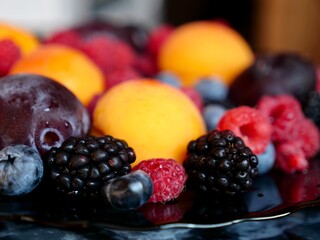 Colored background of seasonal summer fruits apricot, plum, raspberry, blueberry, blackberry in garden, close up