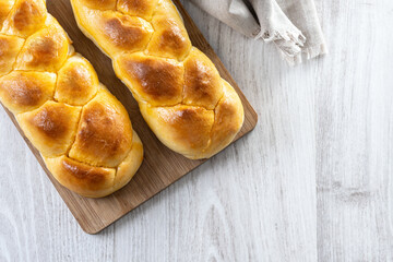Traditional Easter braided bread. Tsoureki braid on white wooden table. Top view. Copy space