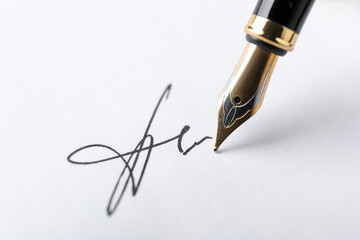 Fountain pen leaving signature on paper, closeup