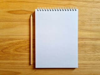 Blank notebook and simple pencil on wooden background