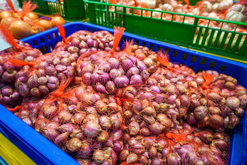 View of many red onions in a basket in a supermarket. Spices and kitchen herbs.