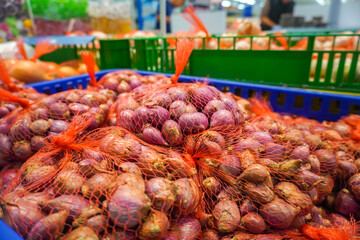 View of many red onions in a basket in a supermarket. Spices and kitchen herbs.