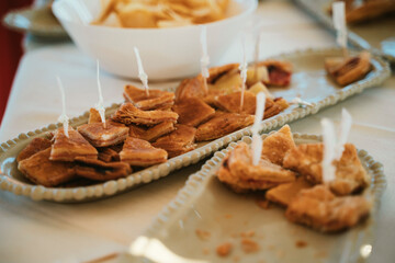 Assorted pastries neatly arranged on ceramic plates, skewered with toothpicks for easy serving at a buffet or gathering. The image highlights the variety and appeal of finger foods