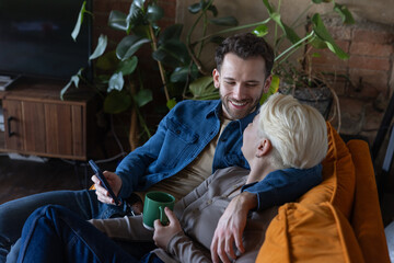 Couple smiling together holding a phone sitting on a couch