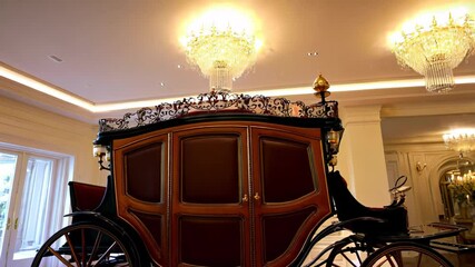 Luxurious antique carriage displayed indoors with elegant lighting and ornate decorative details
- Powered by Adobe