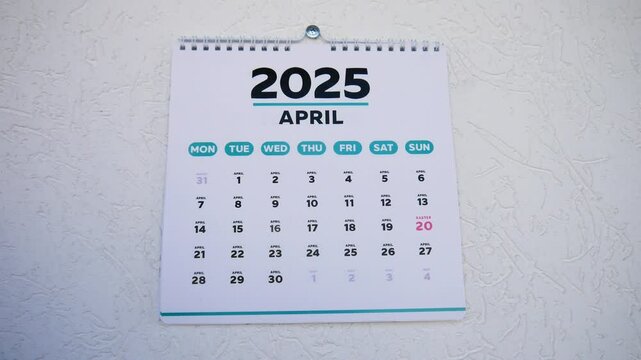 Close-up of male hands tearing off a March page of a wall calendar 2025 to reveal the next one with the marked Easter date