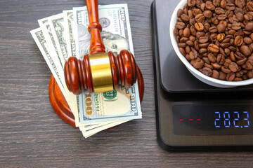 A close-up of a digital scale weighing a bowl of coffee beans, with a wooden gavel and a stack of...