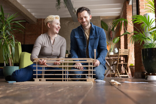 Couple laughing and putting furniture together in their new home