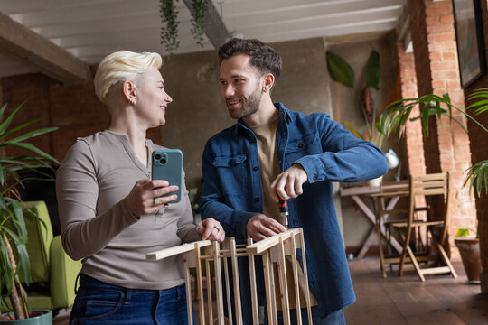 Couple looking at instructions Together on a Phone to build a flat pack