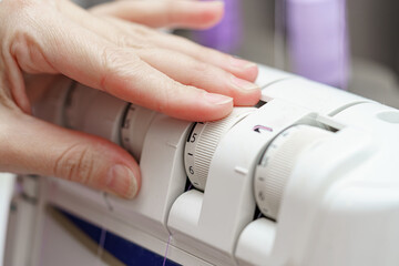 A woman seamstress adjusts the operating modes on a sewing machine. Sewing industry of the textile industry.