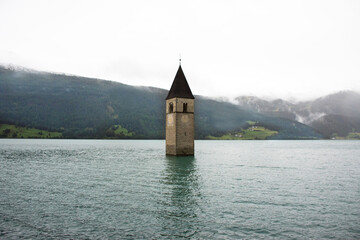 Campanile di curon venosta vecchia or Submerged tower of reschensee church deep in Resias Lake at Bolzano or bozen city at Italy