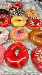 Fresh donuts in the box from the local bakery shop. Mixed freshly baked doughnuts with toppings.