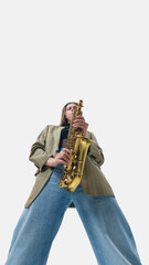 Naklejka premium Low-angle image of passionate woman, saxophonist in vintage blazer confidently playing saxophone, making powerful solo performance. Concept of music, creativity, concert, festival, art, expression