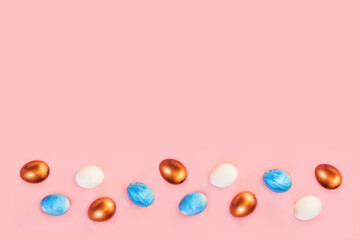 Frame of Easter colorful blue golden and white color eggs on pastel pink background. Stylish trendy gold chocolate egg set isolated. Flat lay, top view, place for text. Happy egg hunt for kids concept