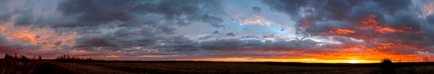 Obraz premium A stunningly beautiful sunset sky and colorful clouds over a field of mown corn.