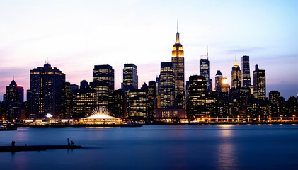 Obraz premium A breathtaking panoramic view of Manhattan’s illuminated skyline at dusk, showcasing towering skyscrapers bathed in golden, blue, and purple hues. The reflective waterfront shimmers with the city's vi