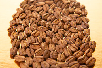 Oval arrangement of roasted coffee beans on a glossy golden surface, emphasizing their earthy hues and natural shine. Great for coffee shop promotions.