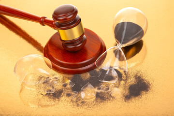 Detailed image of a courtroom gavel paired with a shattered hourglass and black sand, set on a...
