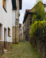 Calle empedrada y estrecha con casas de piedra en Isaba, Navarra, España, en un día nublado.