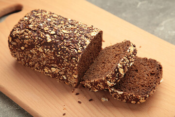 Wheat bread with mixed seeds on cutting board on background