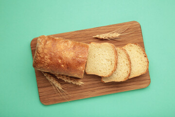 Freshly baked homemade whole grain bread on mint background. Healthy bread on cutting board
