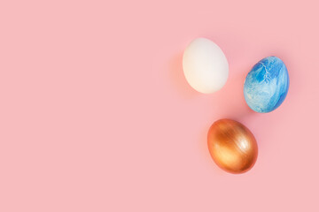 Frame of Easter colorful blue golden and white color eggs on pastel pink background. Stylish trendy gold chocolate egg set isolated. Flat lay, top view, place for text. Happy egg hunt for kids concept