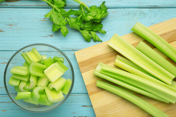 Celery slices in bowl on blue background