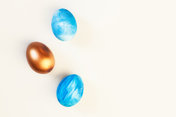 Frame of Easter colorful blue and golden color eggs on pastel pink background. Stylish trendy gold chocolate egg set isolated. Flat lay, top view, place for text. Happy egg hunt for kids concept