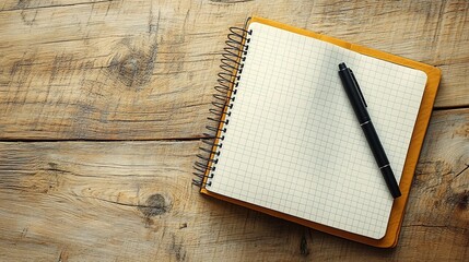 A black pen on the right side of an open notebook with white grid paper, placed on top of a light wood grain table surface. The shot is taken from above and has a shallow depth of field.