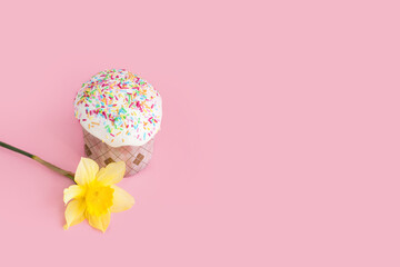 Traditional russian Easter ortodox cake with daffodil flower and colorful eggs on light pink background. Kulic, Kulich, Paska homemade bread with glaze. Spring christian holiday. Festive celebration