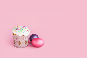 Traditional russian Easter ortodox cake with daffodil flower and colorful eggs on light pink background. Kulic, Kulich, Paska homemade bread with glaze. Spring christian holiday. Festive celebration