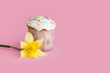 Traditional russian Easter ortodox cake with daffodil flower and colorful eggs on light pink background. Kulic, Kulich, Paska homemade bread with glaze. Spring christian holiday. Festive celebration