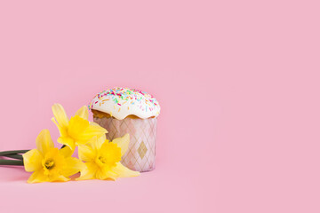 Traditional russian Easter ortodox cake with daffodil flower and colorful eggs on light pink background. Kulic, Kulich, Paska homemade bread with glaze. Spring christian holiday. Festive celebration