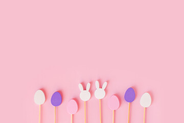 Easter frame composition with minimal style eggs and rabbit wood toys on pastel light pink background. Trendy composition, holiday concept. Flat lay, top view, place for text, card