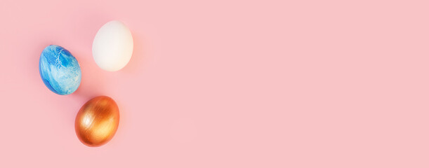 Frame of Easter colorful blue golden and white color eggs on pastel pink background. Stylish trendy gold chocolate egg set isolated. Flat lay, top view, place for text. Happy egg hunt for kids concept