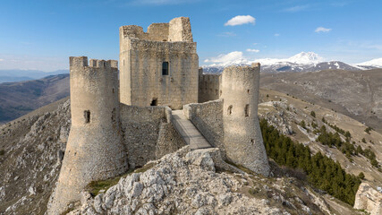 Aerial view of the castle of Rocca Calascio. It is a fortress located in the municipality of Calascio, in Abruzzo, Italy. In the background is the Gran Sasso mountain range with snow-capped peaks.