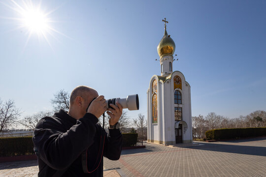 Fototapeta man taking a picture with a professional camera of an Orthodox chapel in Tiraspol, Transnistria - optical illusion