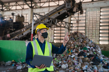 A recycling engineer in a high-visibility vest inspects a waste processing facility, overseeing...