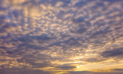 Obraz premium Breathtaking view of a blue sky with soft clouds at sunrise, blending warm yellow and white hues. A serene and cinematic natural sky background perfect for summer-themed designs and scenic wallpapers.