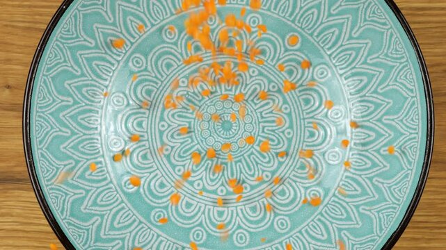 Lentil seeds are poured into a blue ceramic bowl. Top view. Slow motion.